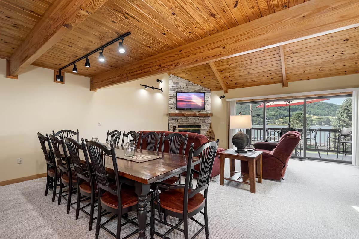 Wood-ceiling dining and living room at the second stay with large windows and balcony doors.