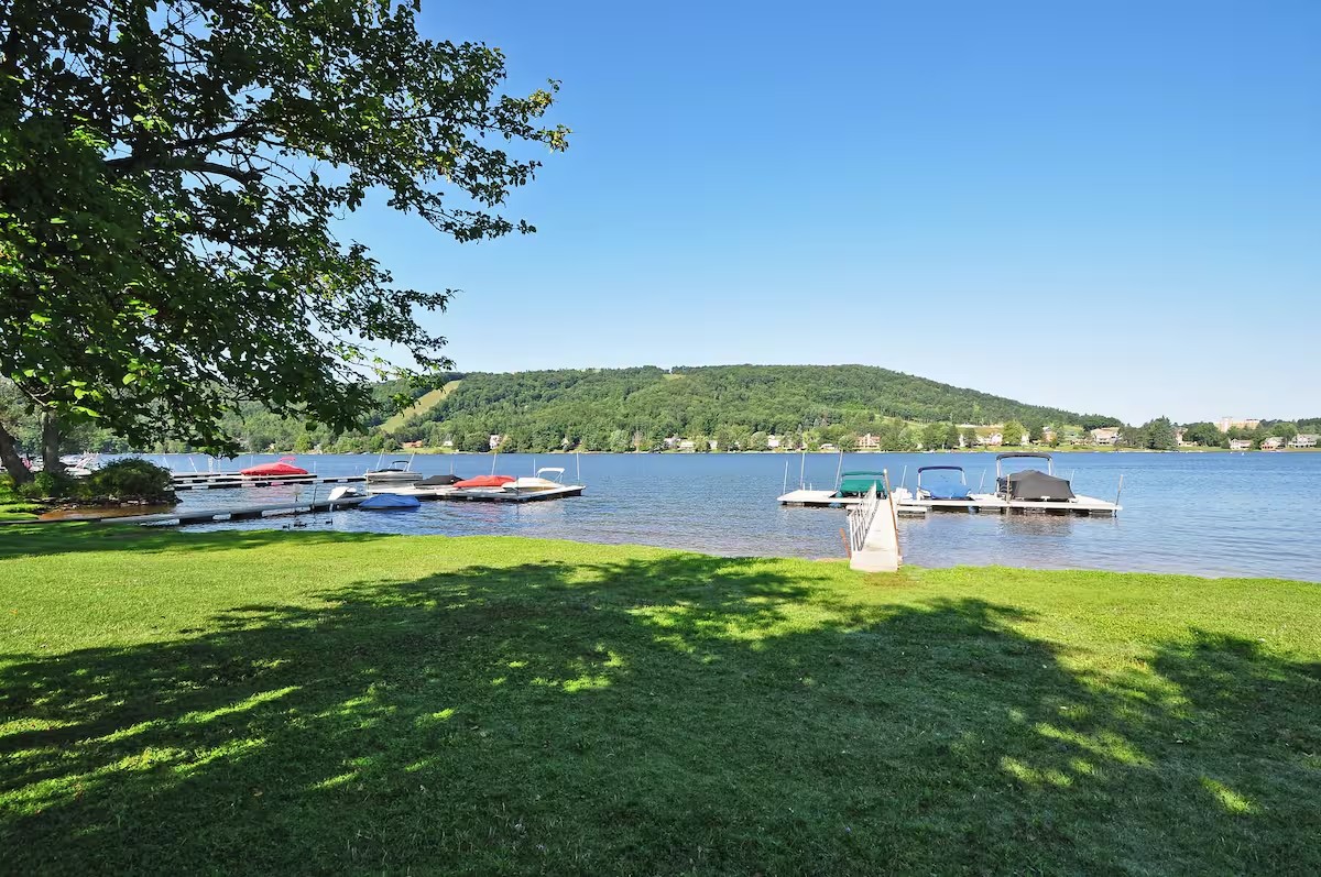 Wide grassy lakefront at Sunplace with docks and forested hills across Deep Creek Lake.